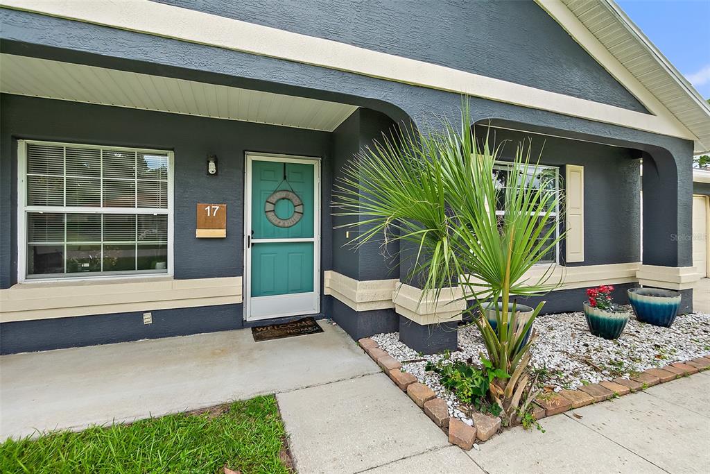 The exterior of a house features a dark gray facade, a teal front door, and landscaping — 17 PINELARK LANE, PALM COAST, FL