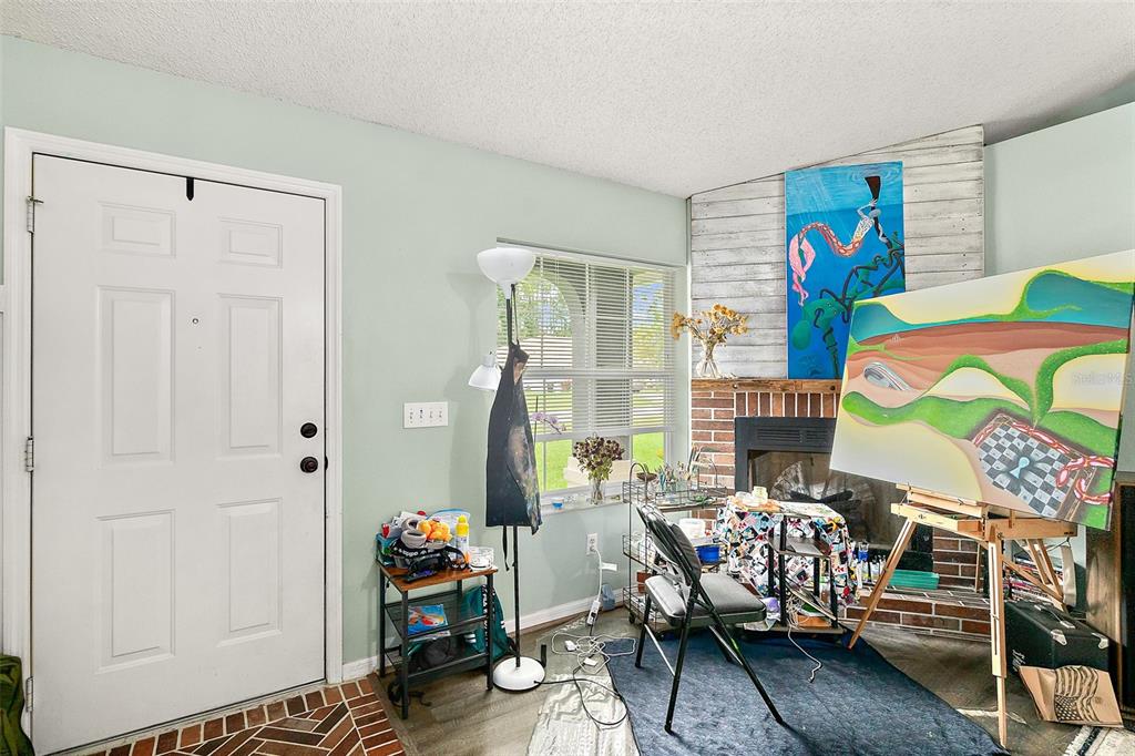 An art studio space features a white front door, a brick fireplace, and an easel — 17 PINELARK LANE, PALM COAST, FL