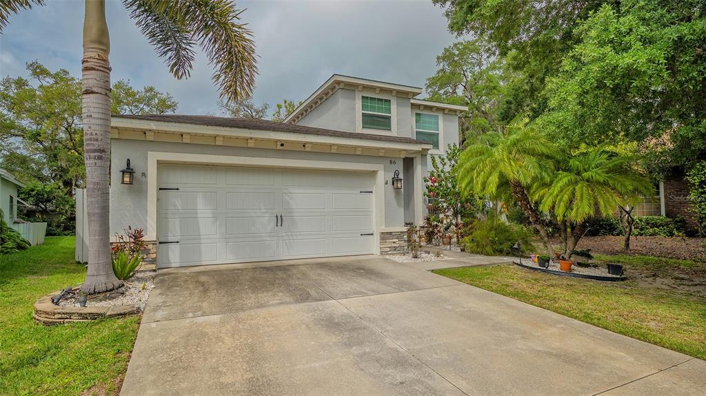 A two-story house with a white garage door, a concrete driveway, and palm trees — 86 ARBOR OAKS DRIVE, SARASOTA, FL