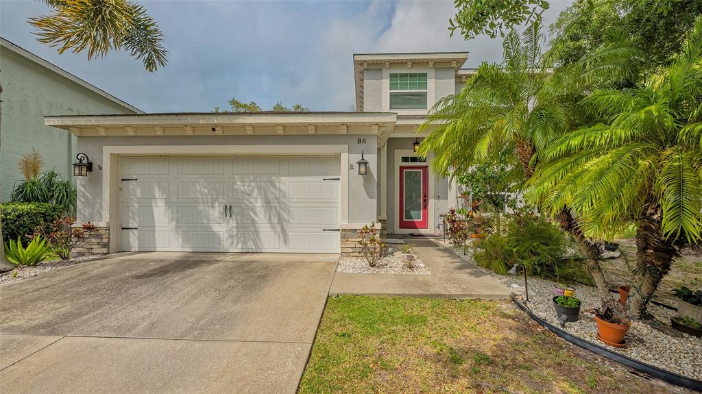 A two-story house with a white garage, a red front door, and palm trees — 86 ARBOR OAKS DRIVE, SARASOTA, FL
