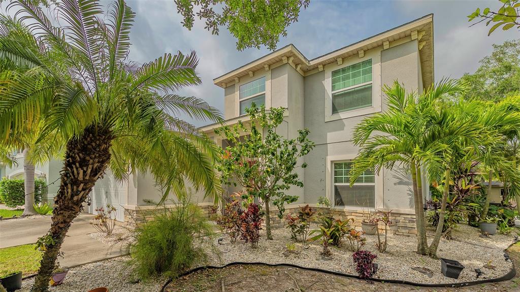 A two-story house with a light-colored stucco exterior, stone accents, and palm trees in front — 86 ARBOR OAKS DRIVE, SARASOTA, FL