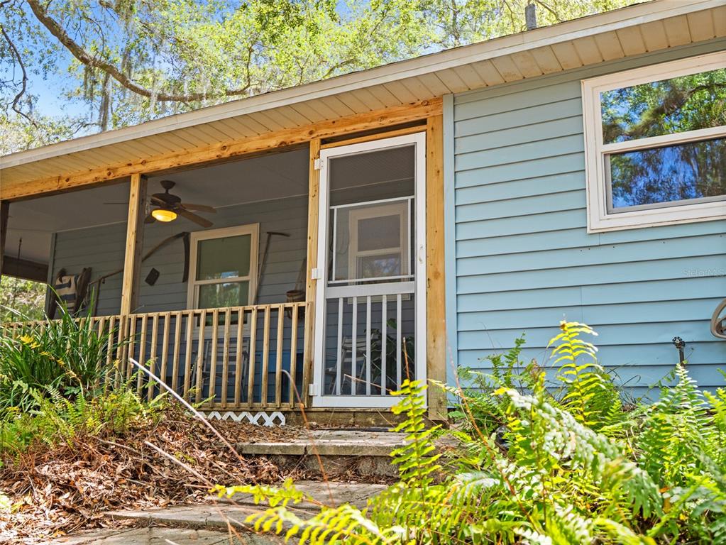 A screened-in porch with a wooden railing and a screen door attached to a house — 255 MOCKINGBIRD LANE, MERRITT ISLAND, FL
