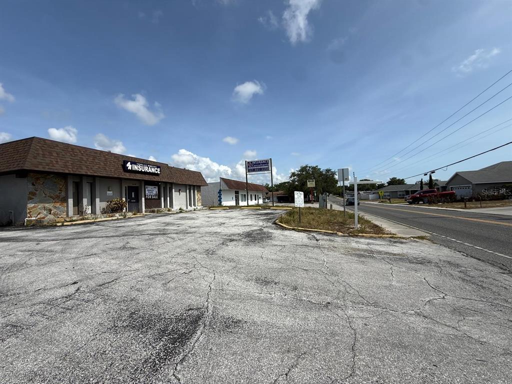 An exterior view of a commercial building with a large paved parking lot — 11640 ZIMMERMAN ROAD, PORT RICHEY, FL