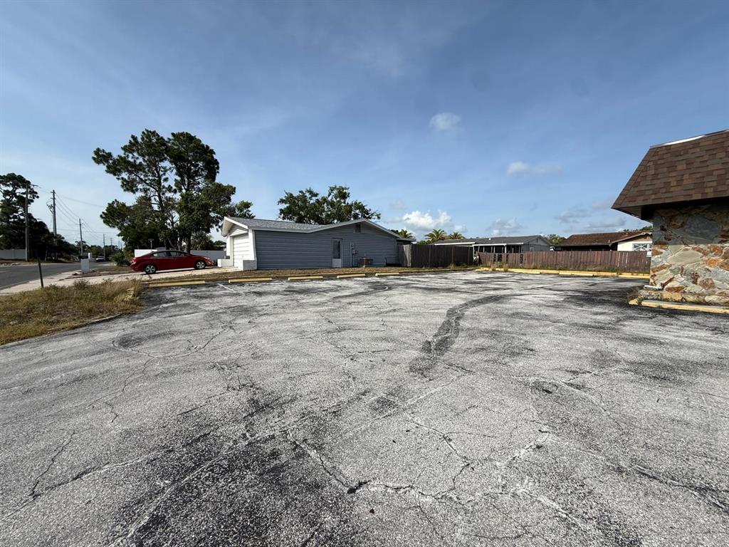 A large, cracked asphalt parking lot sits in front of a gray-sided building — 11640 ZIMMERMAN ROAD, PORT RICHEY, FL