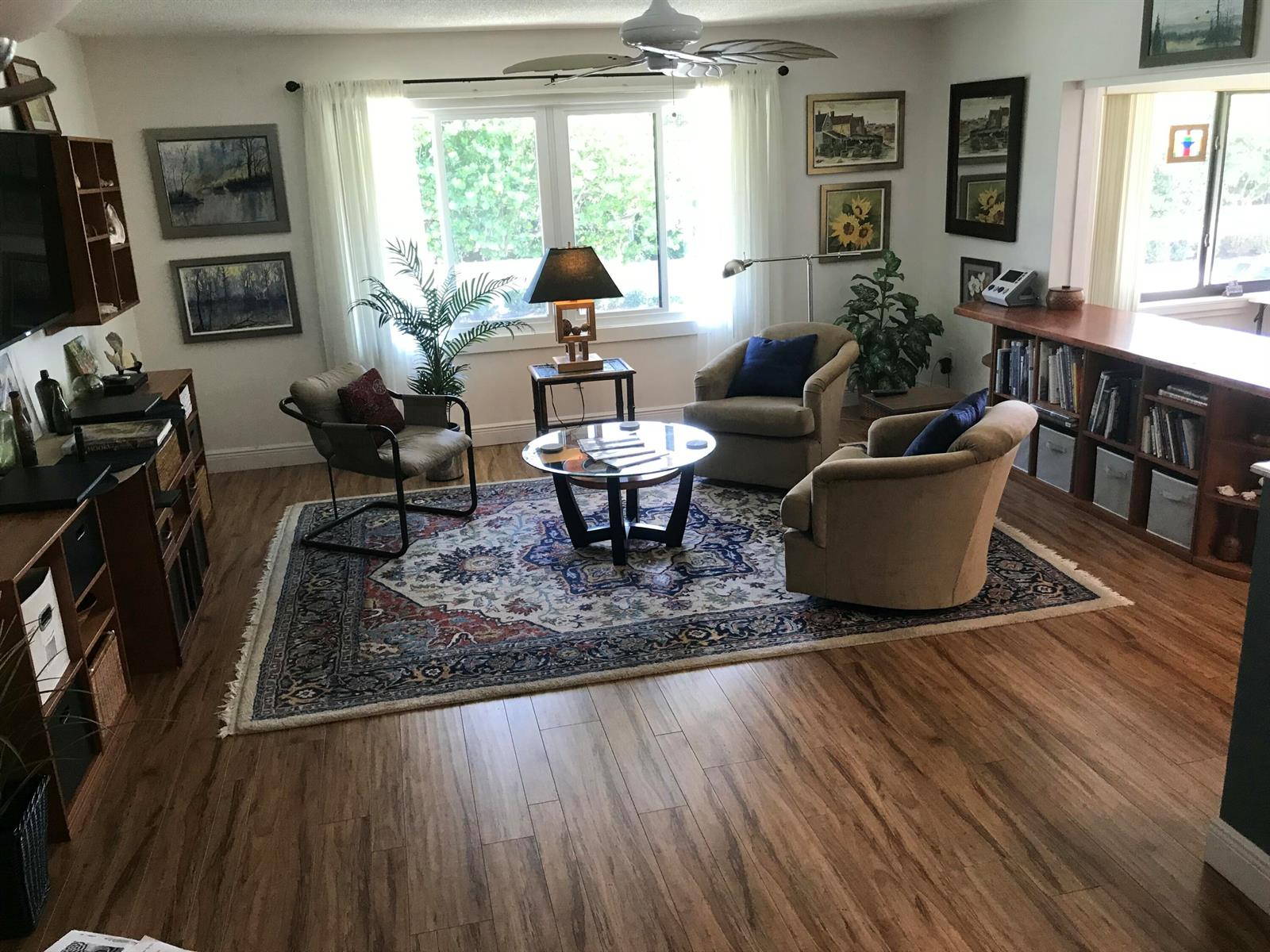 A living room features a patterned area rug, three armchairs, a glass coffee table, and shelving — 1800 SE Saint Lucie Boulevard # 203, Stuart FL 34996, STUART, FL