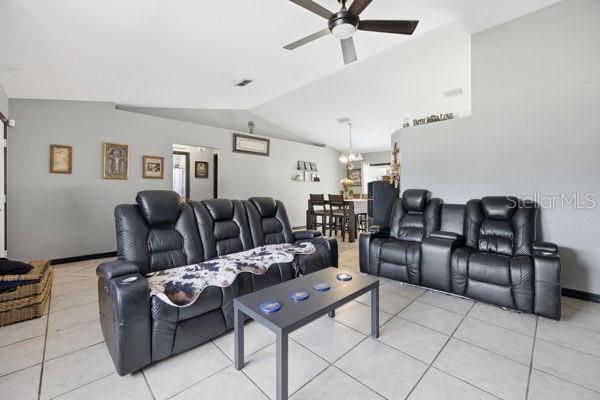 A living room features black leather reclining sofas, a coffee table, and tile flooring — 13185 SW 2ND COURT, OCALA, FL