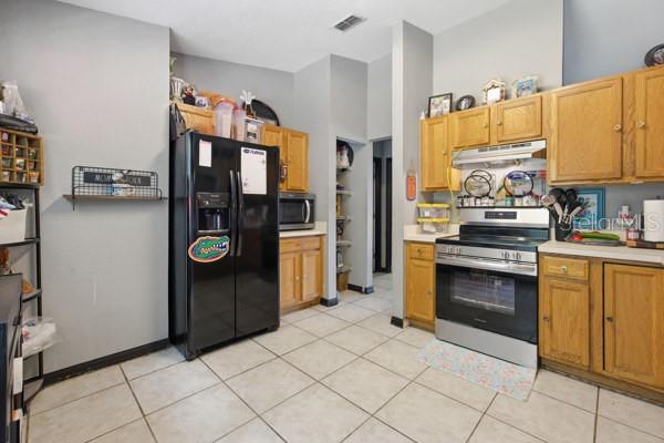 A kitchen features light wood cabinets, a black refrigerator, and a stainless steel gas range — 13185 SW 2ND COURT, OCALA, FL