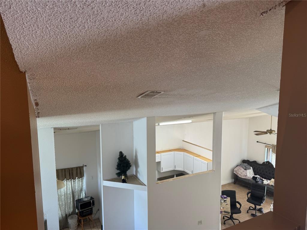 An elevated view looks down into a living area with a popcorn ceiling and kitchen pass-through — 2231 BLUE SAPPHIRE CIRCLE, ORLANDO, FL