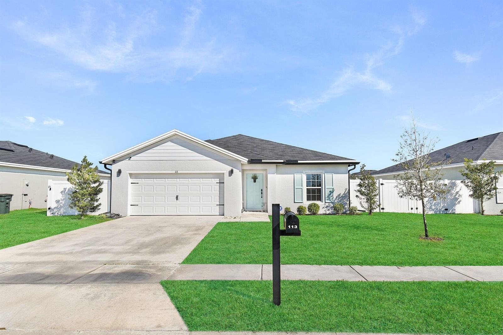 A single-story house with a white exterior, a two-car garage, and a front lawn — 113 Dabou Loop, Belle Glade FL 33430, BELLE GLADE, FL