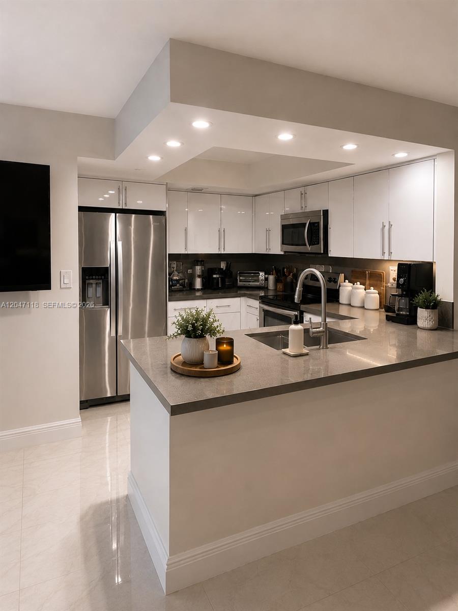 A modern kitchen features white cabinets, stainless steel appliances, and a gray quartz countertop island — 9280 SW 123rd Ct # 106, Miami FL 33186, MIAMI, FL