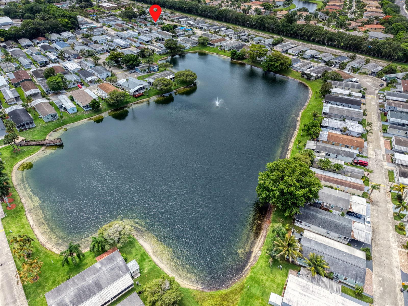 An aerial view shows a residential community surrounding a large pond with a fountain — 59 Plantation Blvd, Lake Worth FL 33467, LAKE WORTH, FL