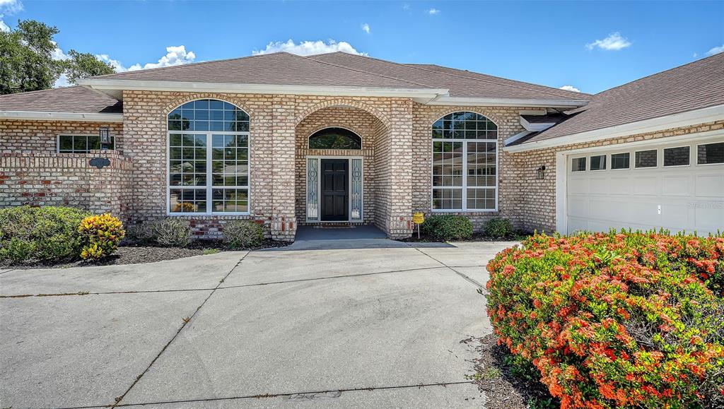 A single-story brick house features a central arched entryway and a multi-car garage — 4360 BRANDYWINE DRIVE, SARASOTA, FL