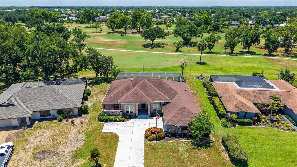 An aerial view shows three suburban houses with brown roofs situated along a golf course — 4360 BRANDYWINE DRIVE, SARASOTA, FL