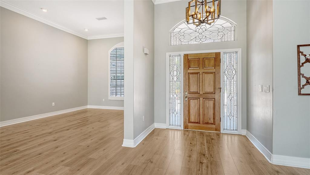 A bright entryway features light wood flooring, a wooden front door, and a decorative chandelier — 4360 BRANDYWINE DRIVE, SARASOTA, FL