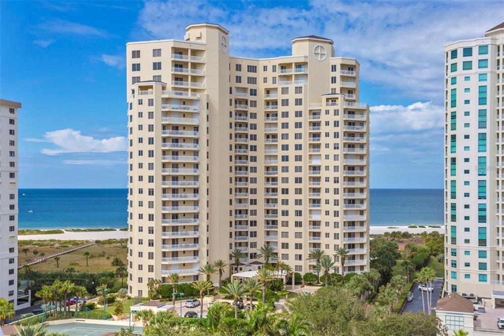 An exterior view of a tall, multi-story residential building located near a sandy beach — 1200 GULF BOULEVARD UNIT 1002, CLEARWATER BEACH, FL