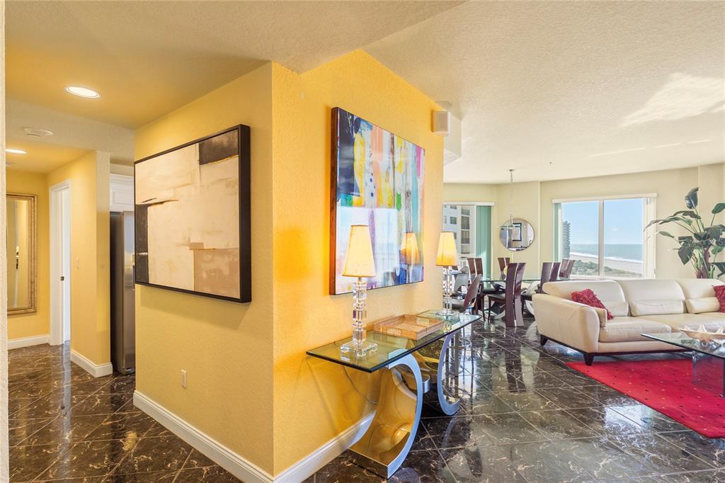 A living and dining area features yellow walls, dark marble floors, and ocean views — 1200 GULF BOULEVARD UNIT 1002, CLEARWATER BEACH, FL