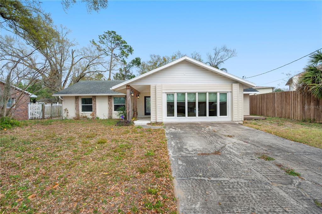 A single-story house with a concrete driveway, a large front window, and a covered entryway — 132 ALACHUA DRIVE, WINTER HAVEN, FL