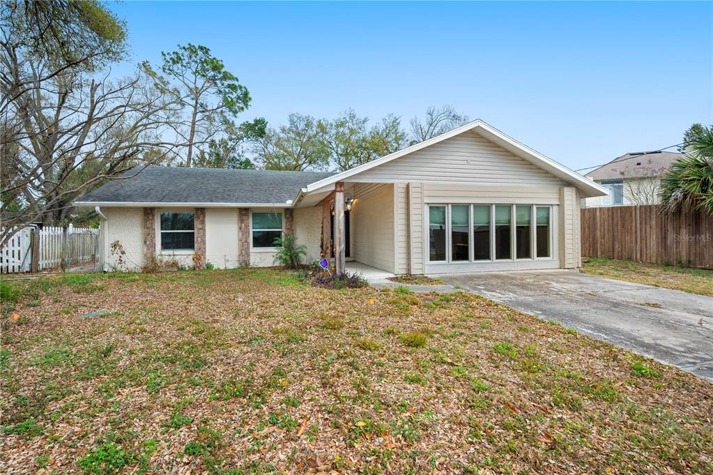 A single-story house with a beige exterior, a concrete driveway, and a large front yard — 132 ALACHUA DRIVE, WINTER HAVEN, FL