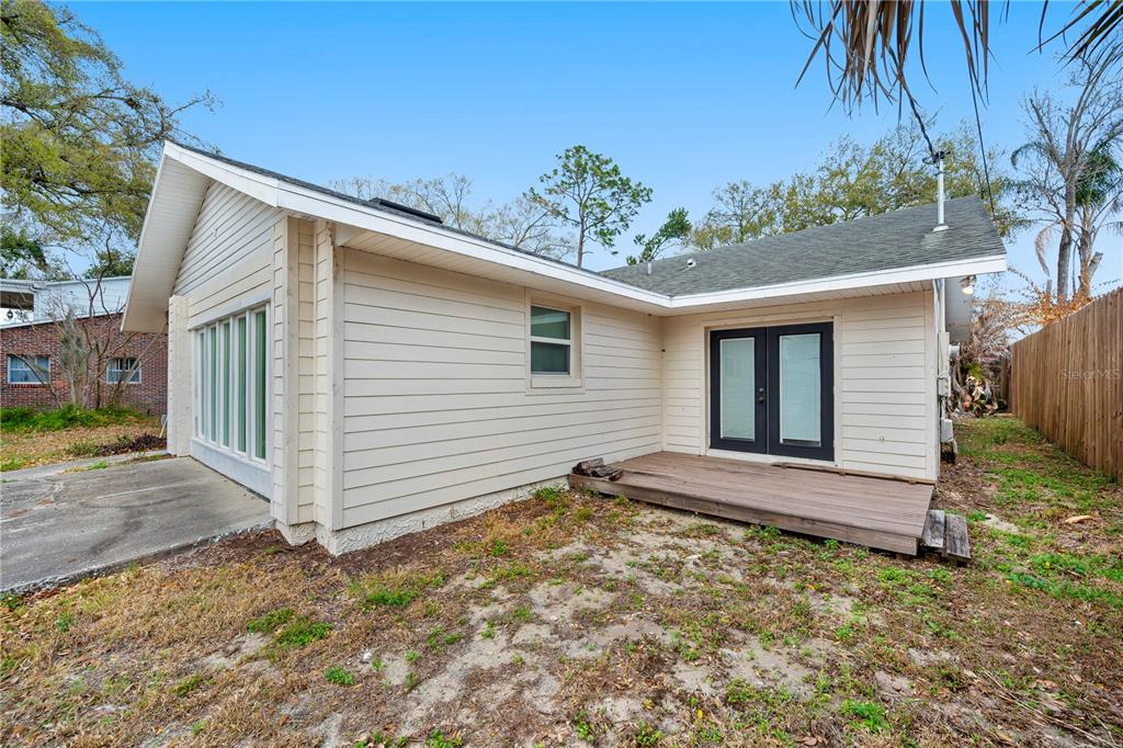 The exterior of a house features beige horizontal siding, a small wooden deck, and windows — 132 ALACHUA DRIVE, WINTER HAVEN, FL