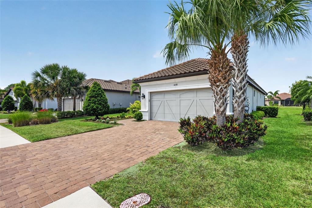 A single-story house with a paved driveway, two-car garage, and palm trees in the front yard — 5238 MOREY FARMS LOOP, PALMETTO, FL