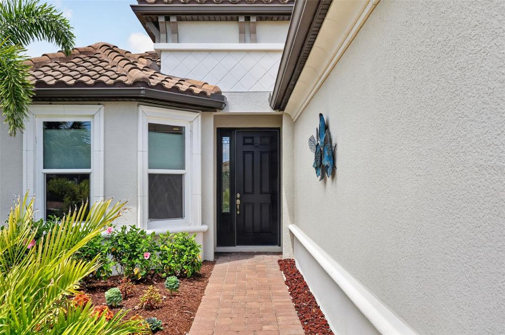 A brick walkway leads to the front entrance of a house with a black door — 5238 MOREY FARMS LOOP, PALMETTO, FL