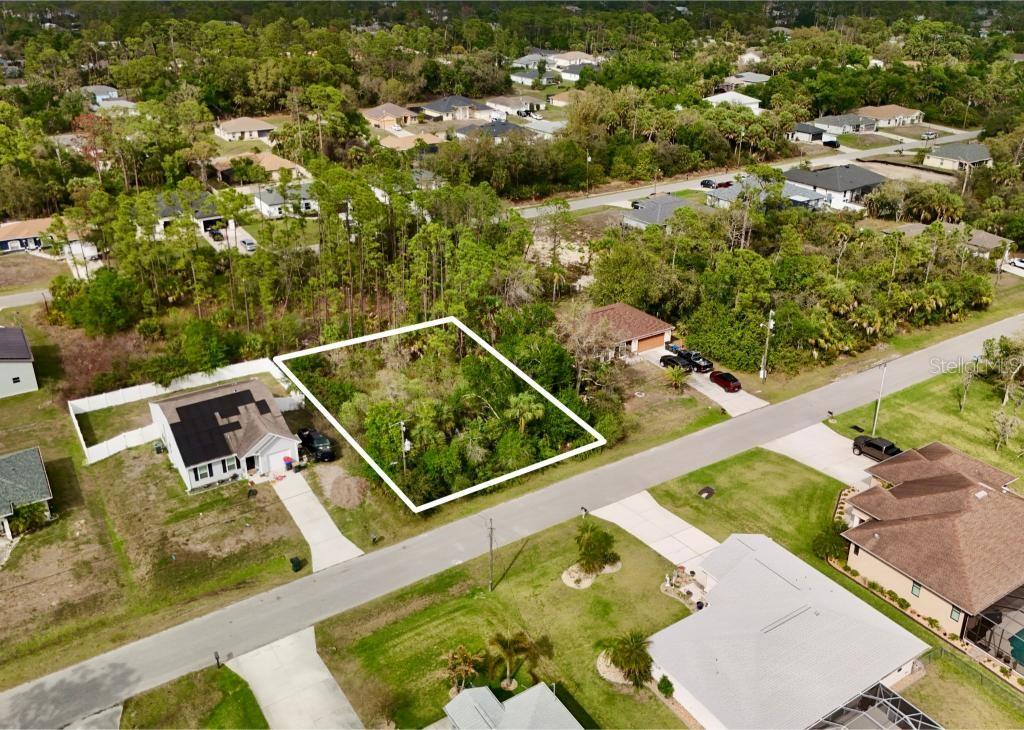 An aerial view shows a vacant, wooded residential lot outlined in white between two houses — LA ROSA AVENUE, NORTH PORT, FL