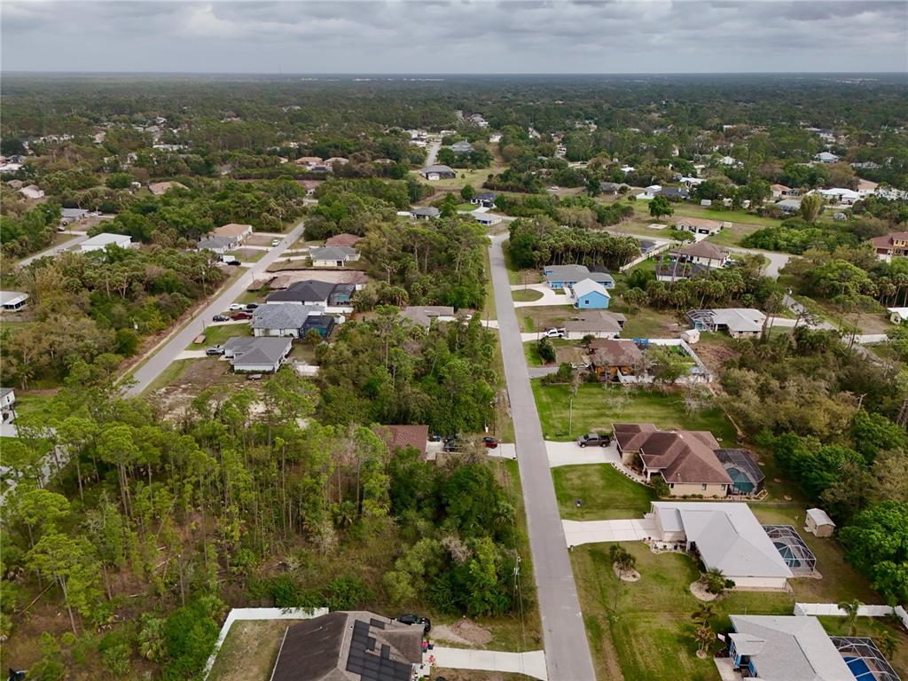 An aerial view shows a residential neighborhood with houses, paved streets, and wooded areas — LA ROSA AVENUE, NORTH PORT, FL