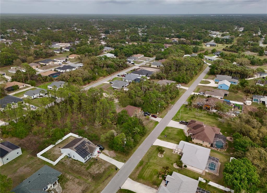 An aerial view shows suburban houses surrounded by trees and vegetation along paved roads — LA ROSA AVENUE, NORTH PORT, FL