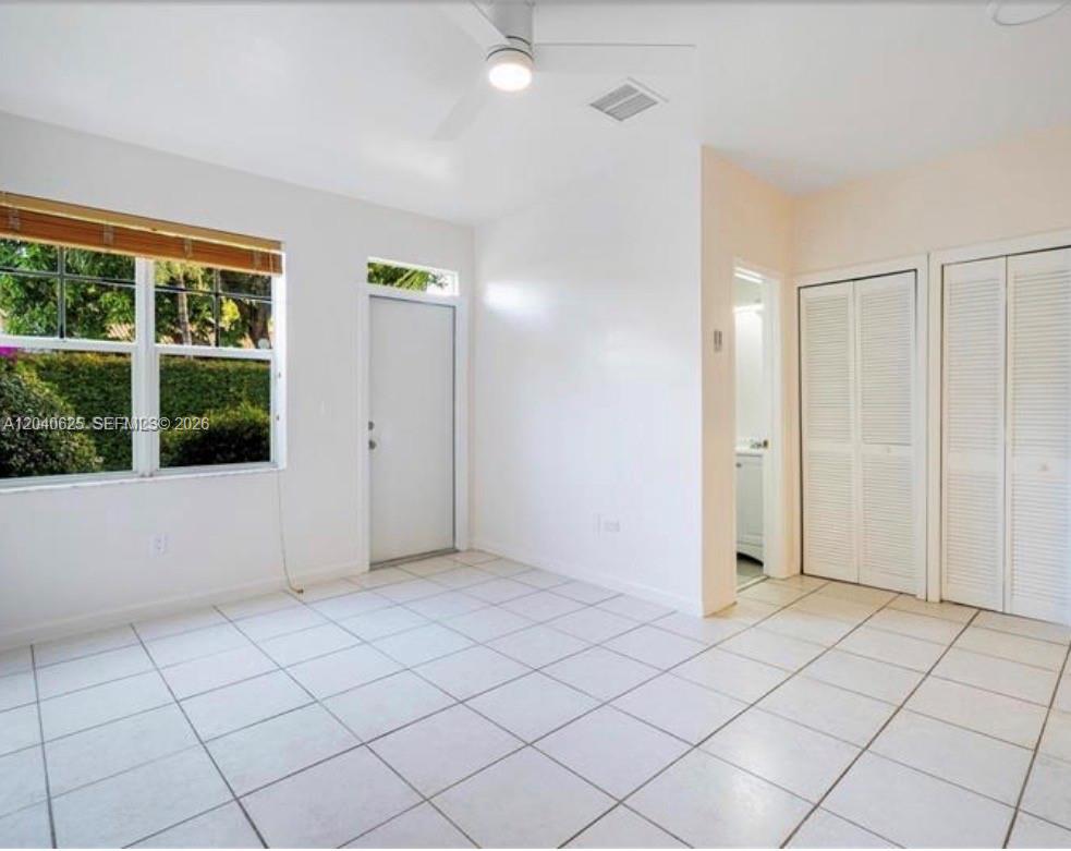 An empty room with white walls, white tile flooring, a ceiling fan, and louvered closet doors — 822 Lenox Ave # 5, Miami Beach FL 33139, MIAMI BEACH, FL