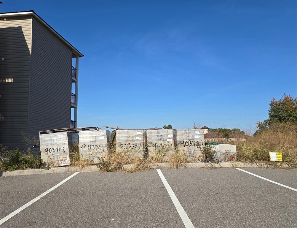 Five stacks of construction materials sit in a paved parking lot next to a building — 811 RETREAT BOULEVARD UNIT 201, DAVENPORT, FL