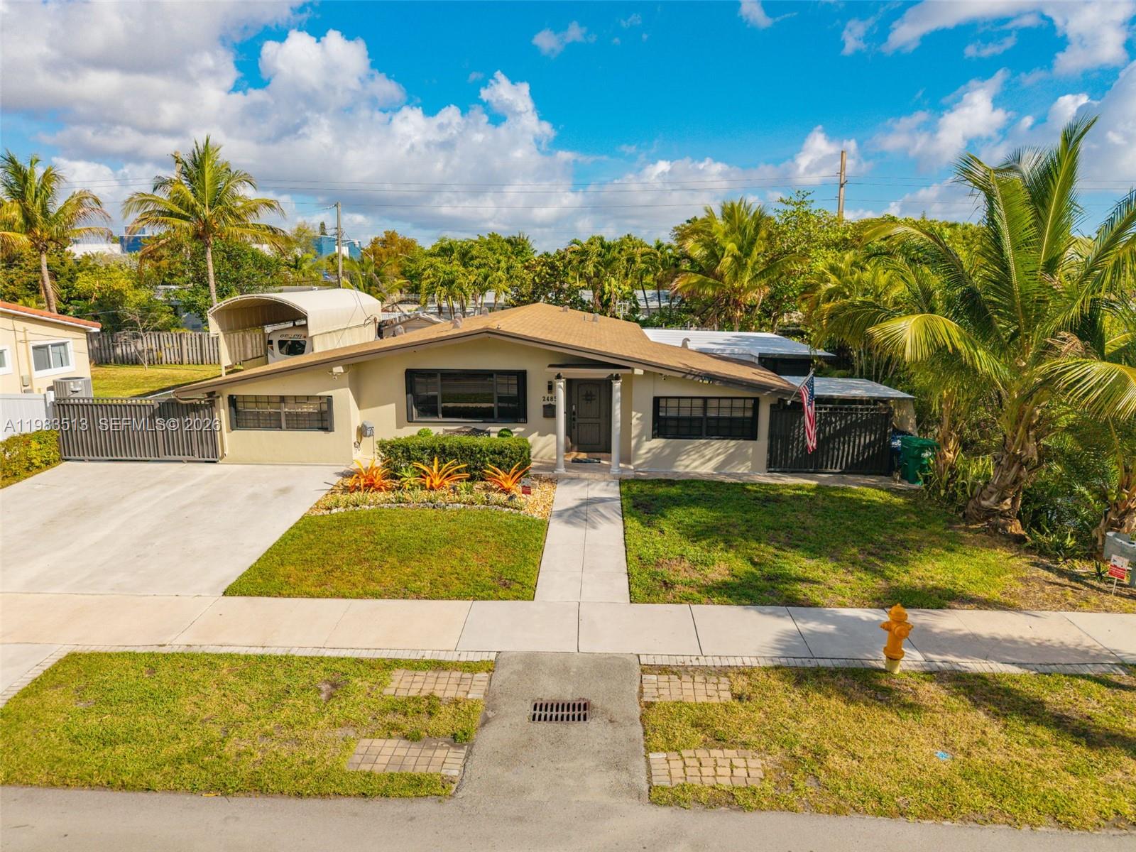 A single-story house with a tan exterior, a concrete driveway, and palm trees in front — 2485 NE 214th St, Miami FL 33180, MIAMI, FL