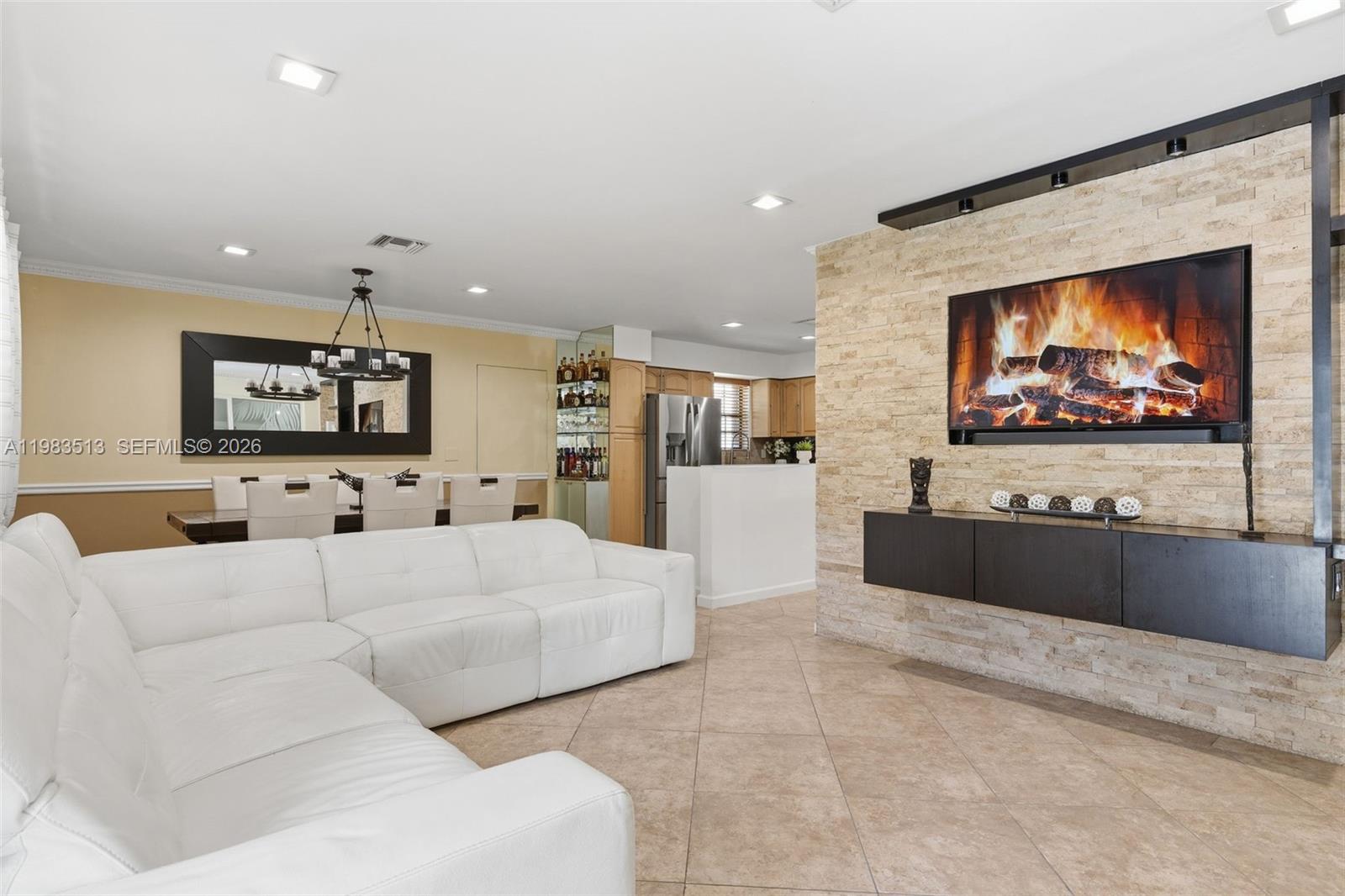 A living room features a white sectional sofa, a stone fireplace wall, and a dining area — 2485 NE 214th St, Miami FL 33180, MIAMI, FL
