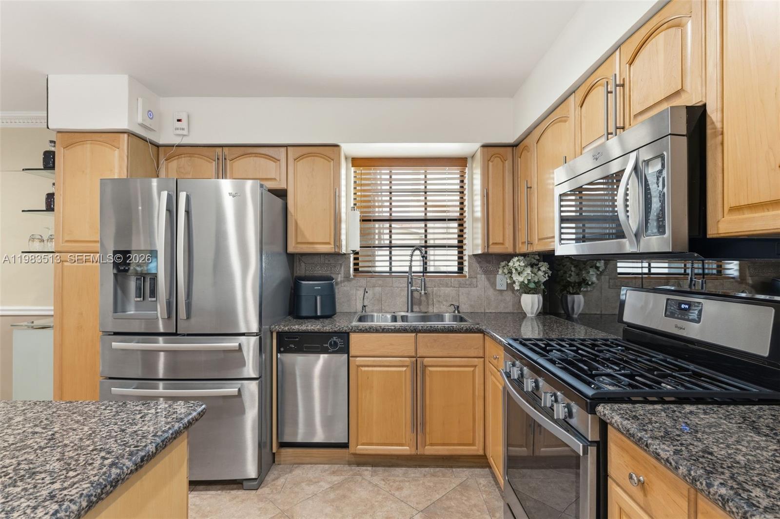A kitchen features light wood cabinets, granite countertops, and stainless steel appliances — 2485 NE 214th St, Miami FL 33180, MIAMI, FL