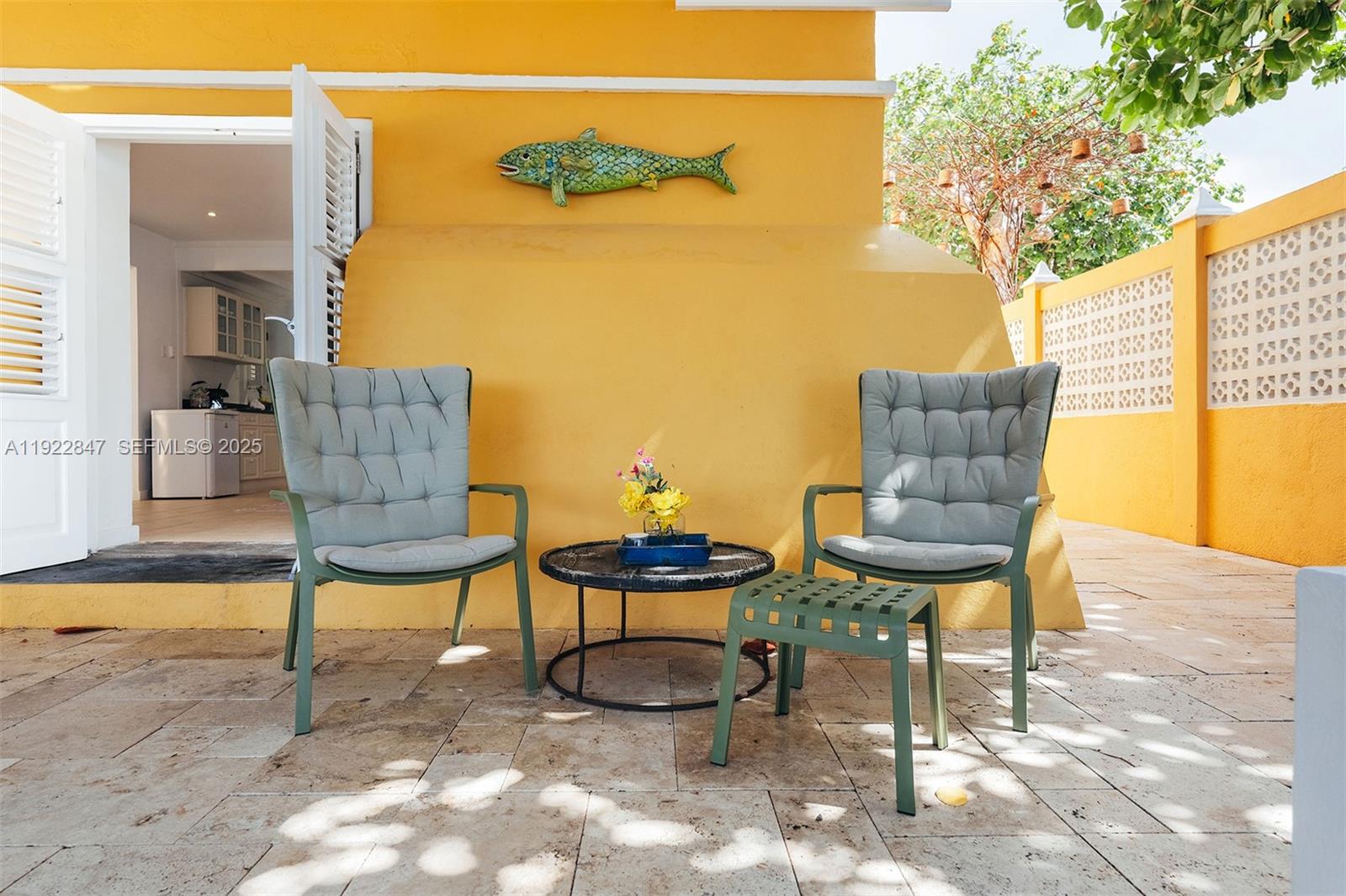 A patio features two gray chairs, a small round table, and a decorative fish wall ornament — 0000 N Penstraat, 0000, FL