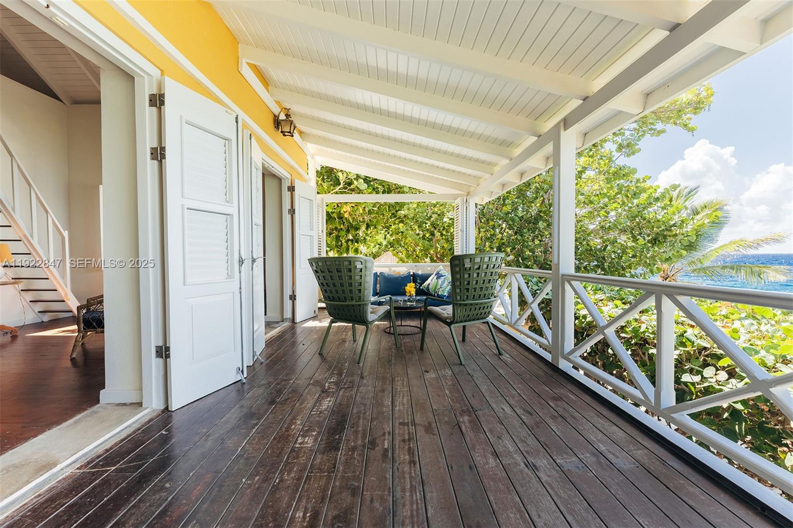 A covered wooden deck features two green chairs and a view of the ocean — 0000 N Penstraat, 0000, FL