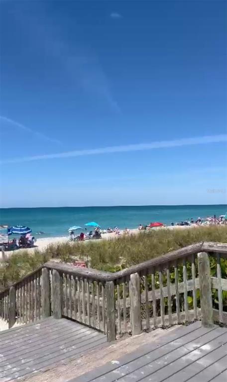 A wooden staircase leads down to a sandy beach with umbrellas and the ocean — 13092 RANKIN AVENUE, PORT CHARLOTTE, FL