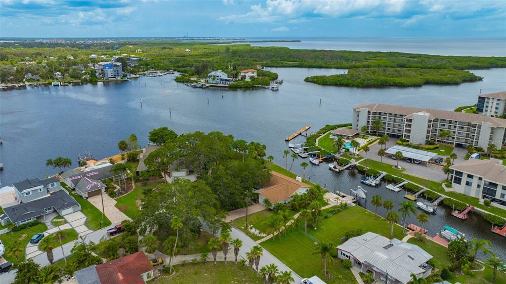 An aerial view shows waterfront homes, a multi-story apartment building, and a canal with boats — 8143 CHANNEL DRIVE, PORT RICHEY, FL