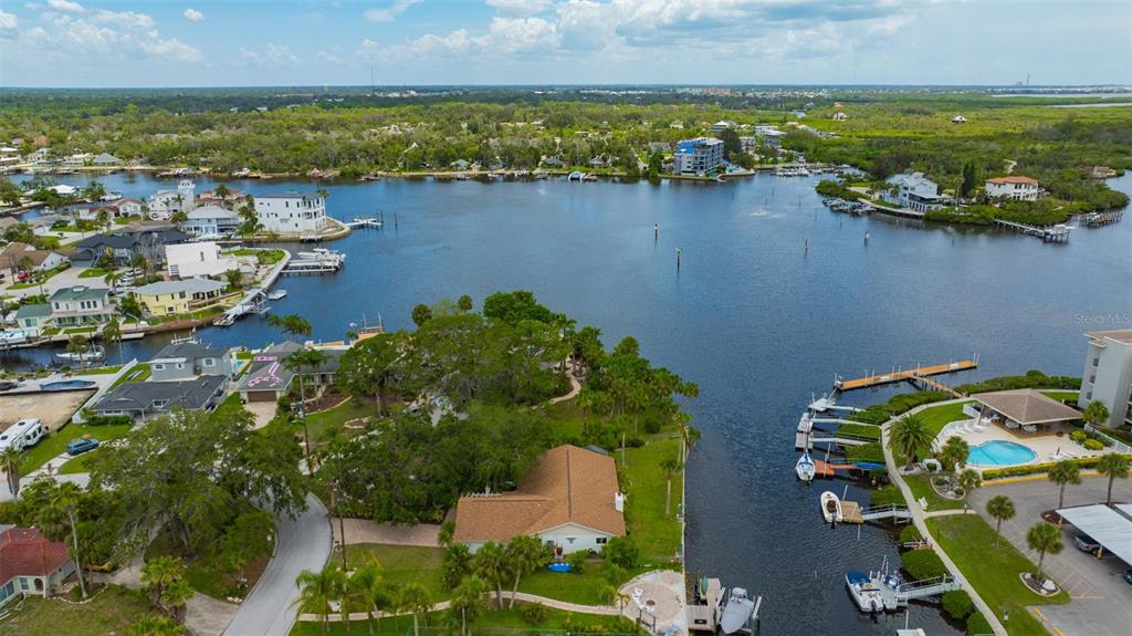 An aerial view shows a waterfront residential area with houses, docks, and a boat canal — 8143 CHANNEL DRIVE, PORT RICHEY, FL