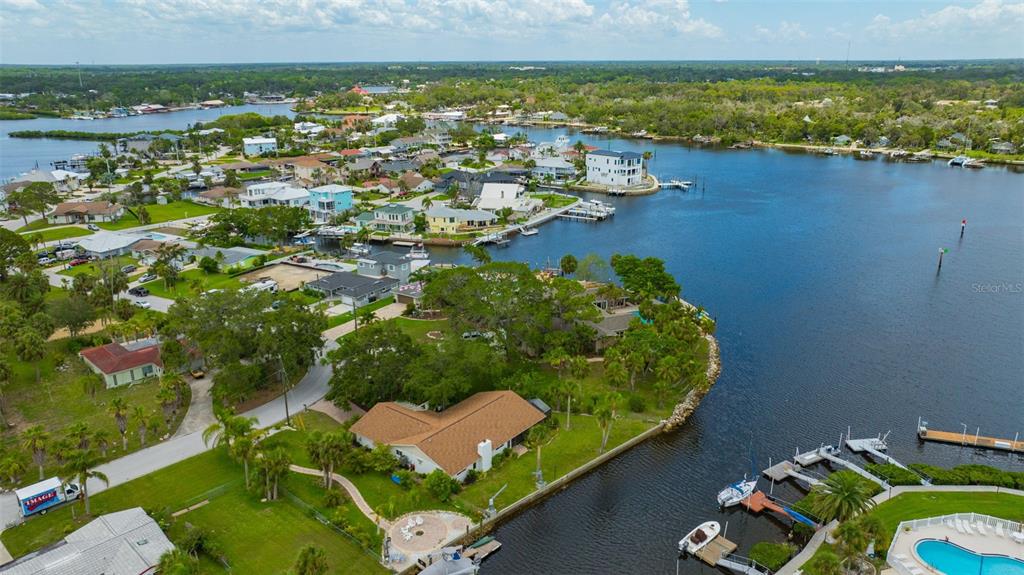 An aerial view shows waterfront homes with docks, boats, and swimming pools along a canal — 8143 CHANNEL DRIVE, PORT RICHEY, FL
