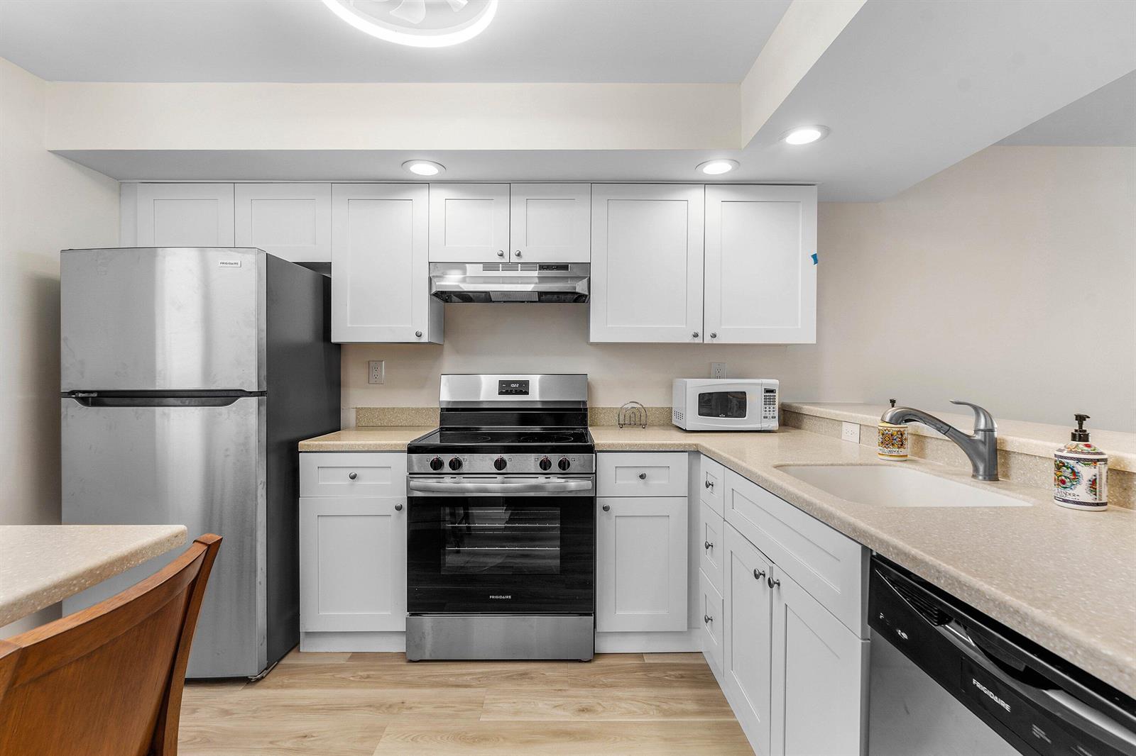 A kitchen features white cabinets, stainless steel appliances, and light-colored countertops — 1950 SW Palm City Road # 14203, Stuart FL 34994, STUART, FL