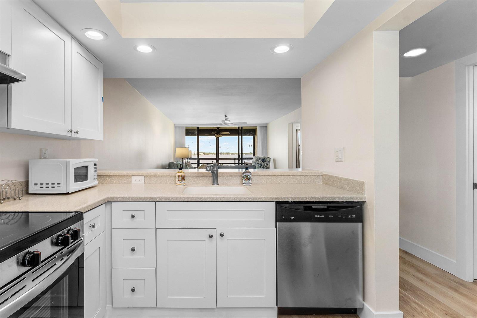 A kitchen with white cabinets, stainless steel appliances, and a view into the living area — 1950 SW Palm City Road # 14203, Stuart FL 34994, STUART, FL