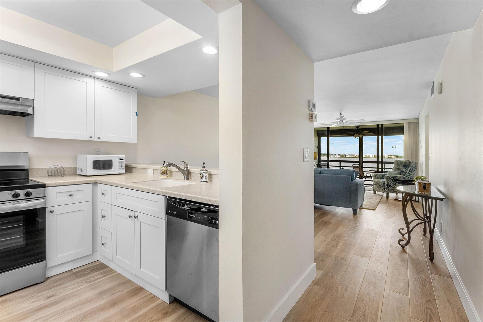 A white kitchen with stainless steel appliances opens into a living area overlooking the water — 1950 SW Palm City Road # 14203, Stuart FL 34994, STUART, FL