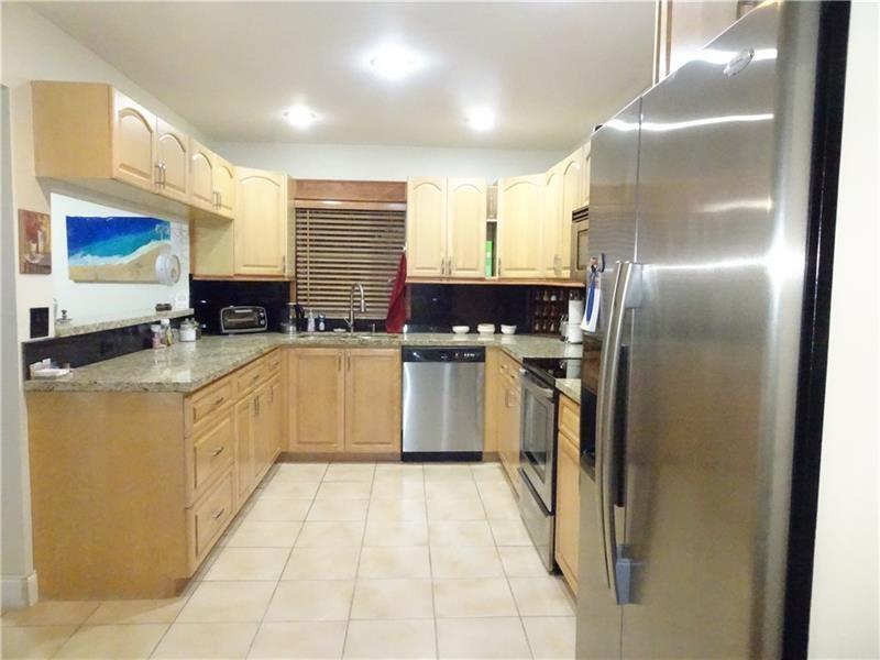 A kitchen features light wood cabinets, granite countertops, stainless steel appliances, and tile flooring — 96 Del Rio Boulevard, Boca Raton FL 33432, BOCA RATON, FL