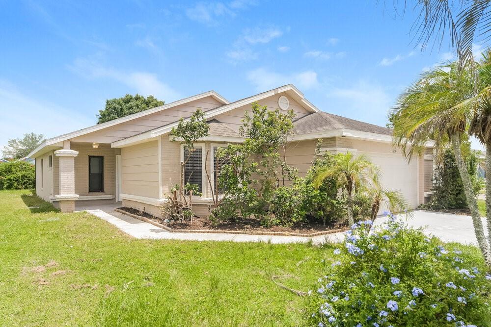 A single-story house with beige siding, a front-facing garage, and a landscaped front yard — 13230 BOULDER WOODS CIRCLE, ORLANDO, FL