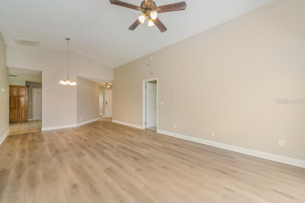 An empty room with light wood-look flooring, high ceilings, a ceiling fan, and white walls — 13230 BOULDER WOODS CIRCLE, ORLANDO, FL