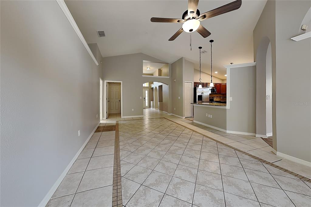 An open-concept living area features vaulted ceilings, tile flooring, and a kitchen with pendant lighting — 2517 CLARESIDE DRIVE, VALRICO, FL