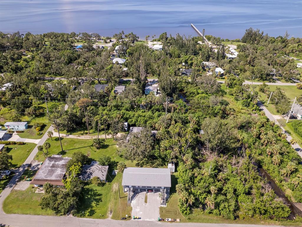 An aerial view shows a residential property with a multi-story building and surrounding wooded area — 23019 SENECA AVENUE, PORT CHARLOTTE, FL