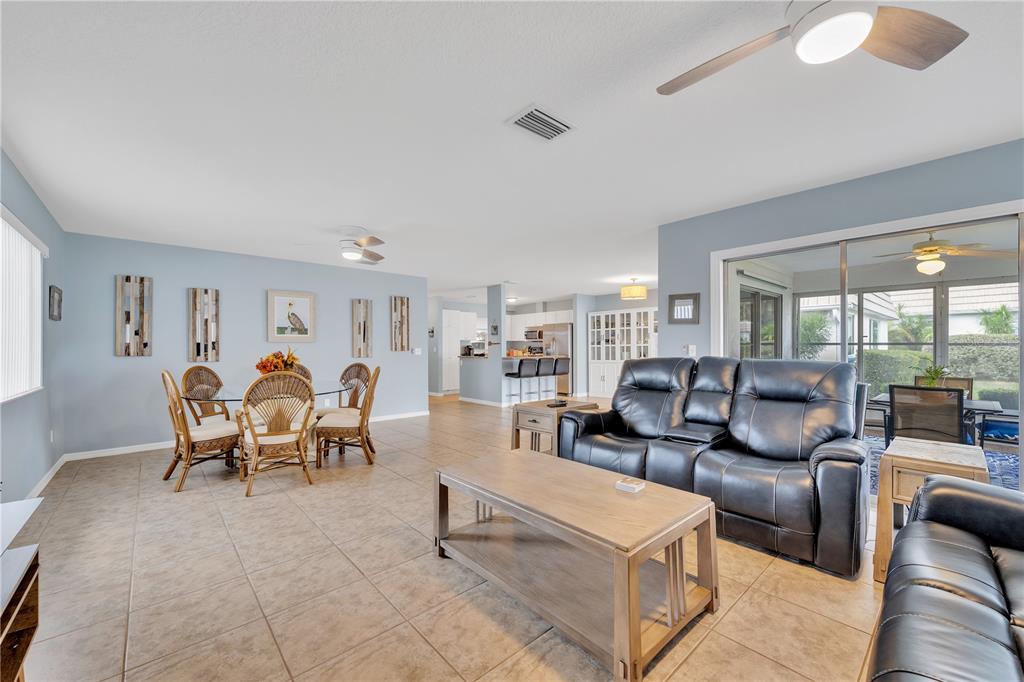 An open-concept living and dining area features light blue walls, tile flooring, and leather furniture — 2401 RIVERBLUFF PARKWAY UNIT V240, SARASOTA, FL