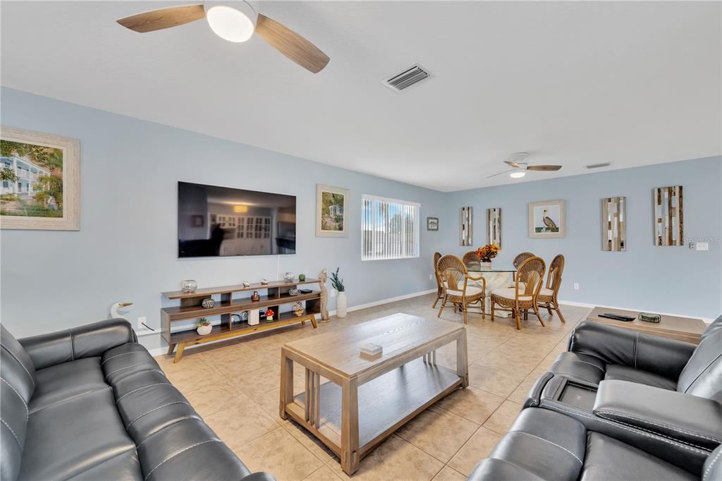 A living room with light blue walls, tile flooring, two leather sofas, and a dining area — 2401 RIVERBLUFF PARKWAY UNIT V240, SARASOTA, FL