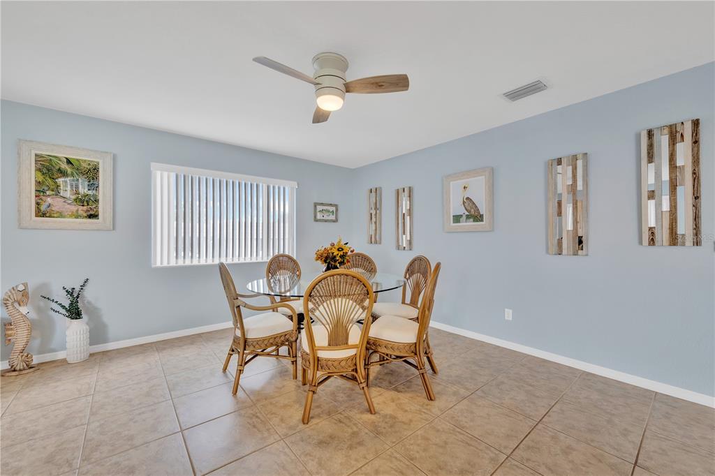 A dining room with a glass table, wicker chairs, light blue walls, and tile flooring — 2401 RIVERBLUFF PARKWAY UNIT V240, SARASOTA, FL